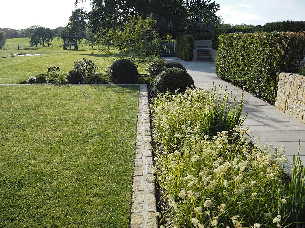 Formal garden gives way to wild English woodlands beyond.
