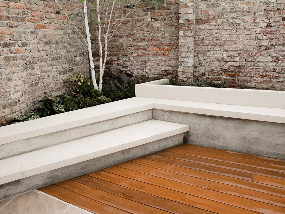 Modern materials like cast concrete alongside natural stone to create a small and modern garden. Seating incorporated into the raised beds means even a tiny space can be sociable.
